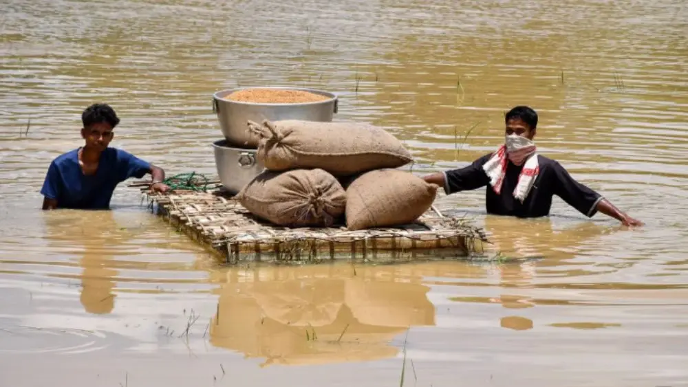 Người dân bang Assam, Ấn Độ vận chuyển lương thực qua vùng ngập lụt bằng bè giữa đợt lũ nghiêm trọng.