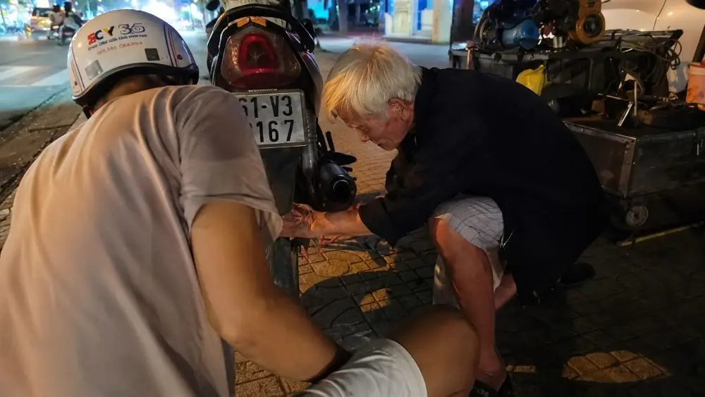 Cụ ông 91 tuổi vẫn bơm xe bên đường, quỳ thấp làm việc vì thoái hóa xương khớp và thoát vị đĩa đệm.